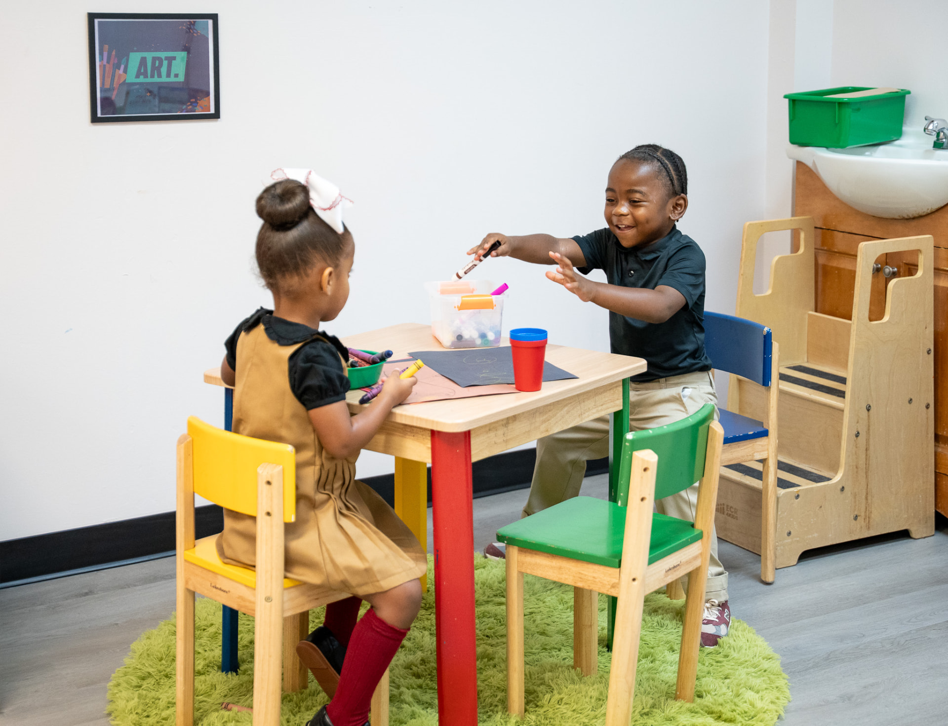 Two children drawing together at a colorful table in The Early Learning Institute classroom