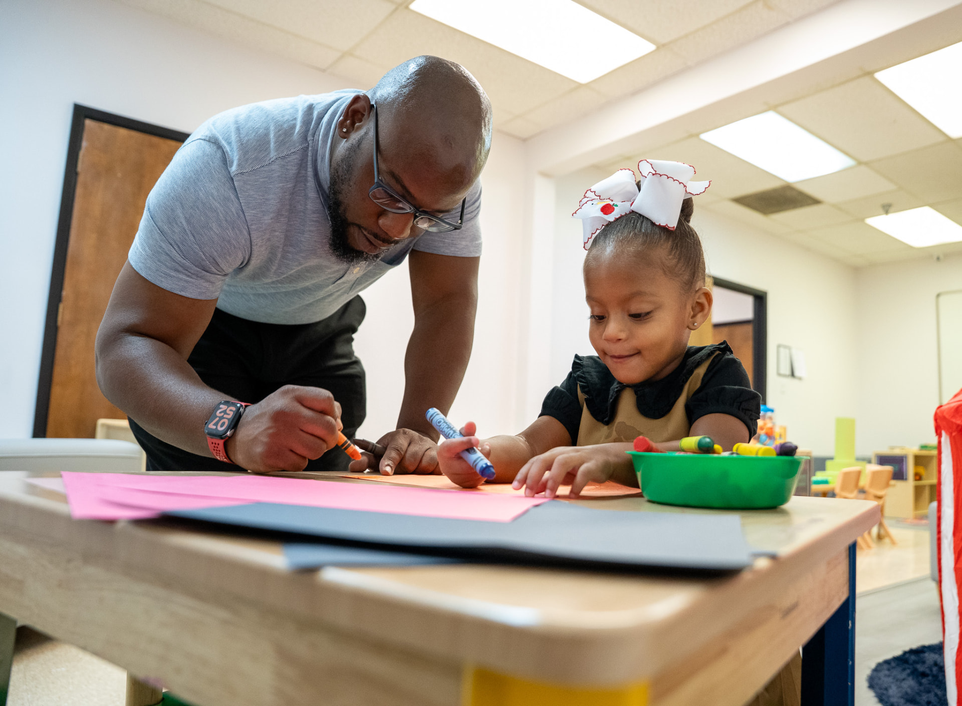 A man and young girl drawing together with crayons in The Early Learning Institute Scholars Division